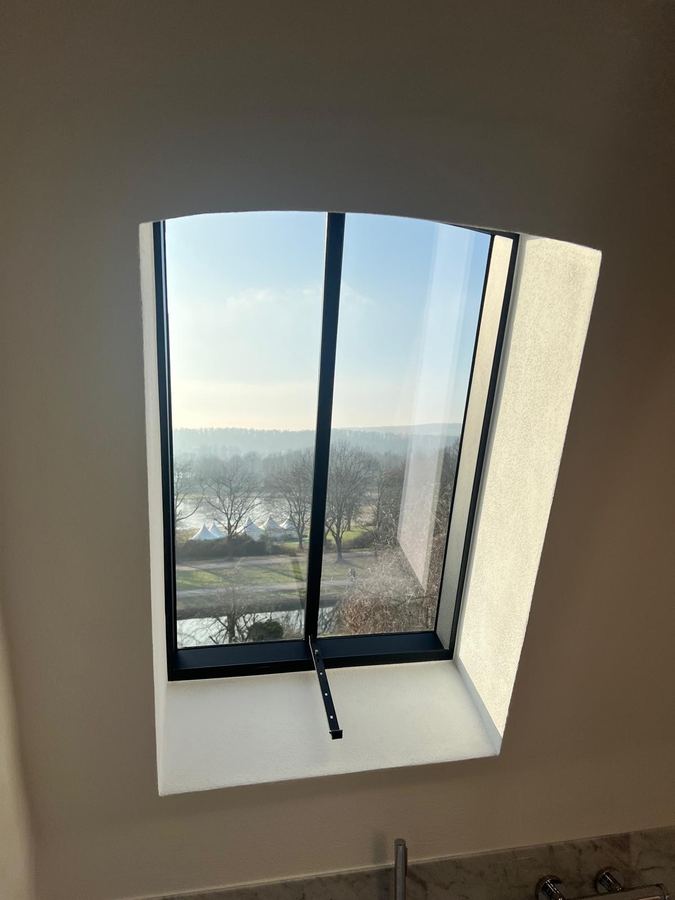 Trapezförmiges Fenster in dicker Wandlaibung mit Blick über die Landschaft