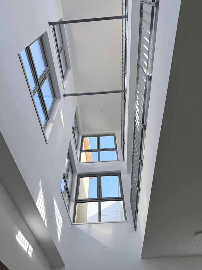 Blick nach oben in einen Luftraum mit Sprossenfenstern und Stahlgeländern