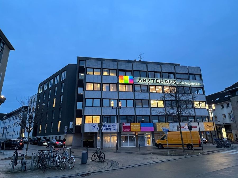 Ärztehaus in der Stadt zur blauen Stunde, beleuchtete Fenster über den Ladenzeilen