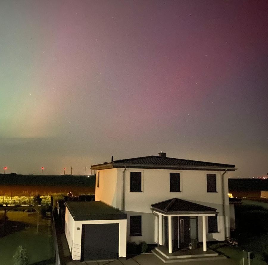 Freistehendes Wohnhaus bei Nacht unter einem rötlich leuchtenden Nachthimmel