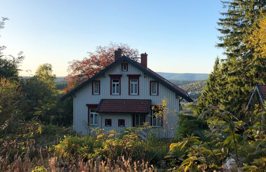 Blau-weißes Holzhaus am Hang mit Blick über die Berge