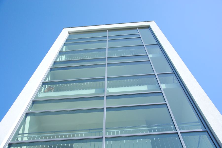 Spitz zulaufende Glasfassade eines Bürogebäudes vor blauem Himmel