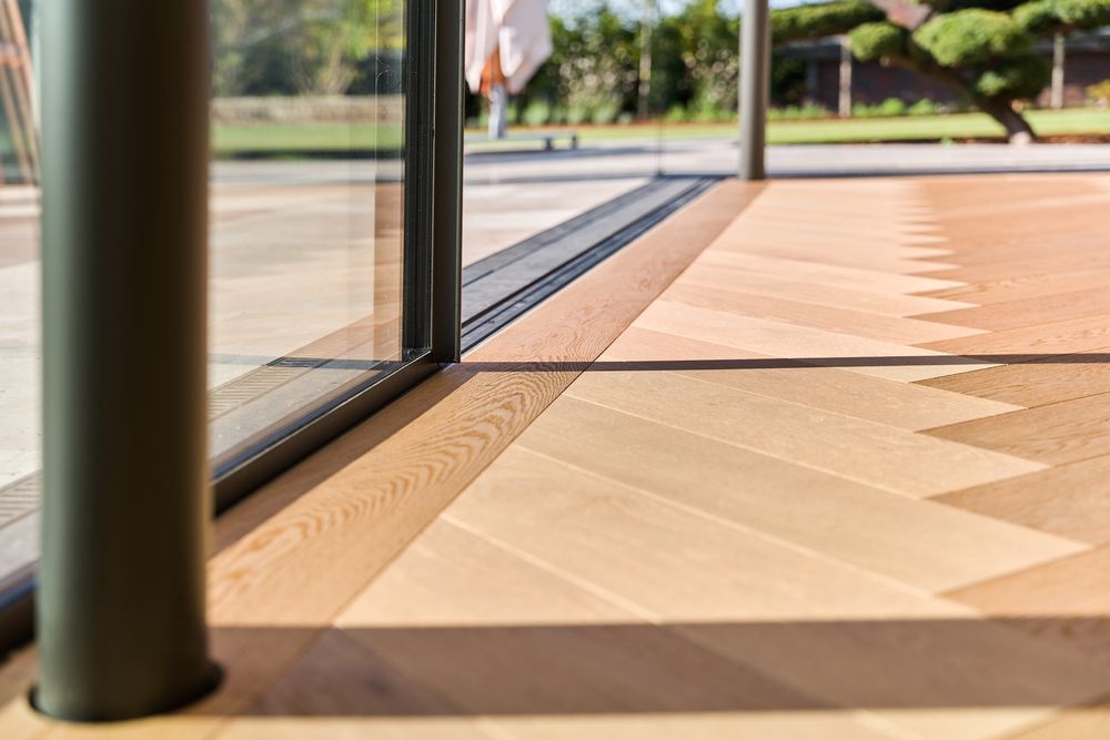 Detail einer Fensterlaibung mit Blick auf ein Parkett im Fischgrätmuster