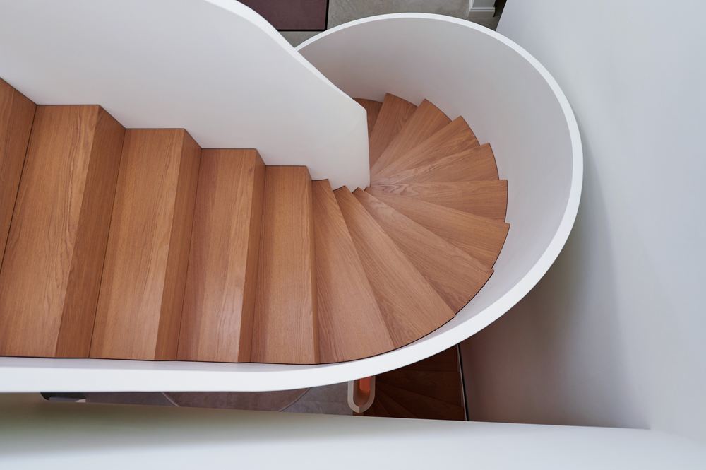Gewendelte Holztreppe von oben gesehen, mit weißer Brüstung