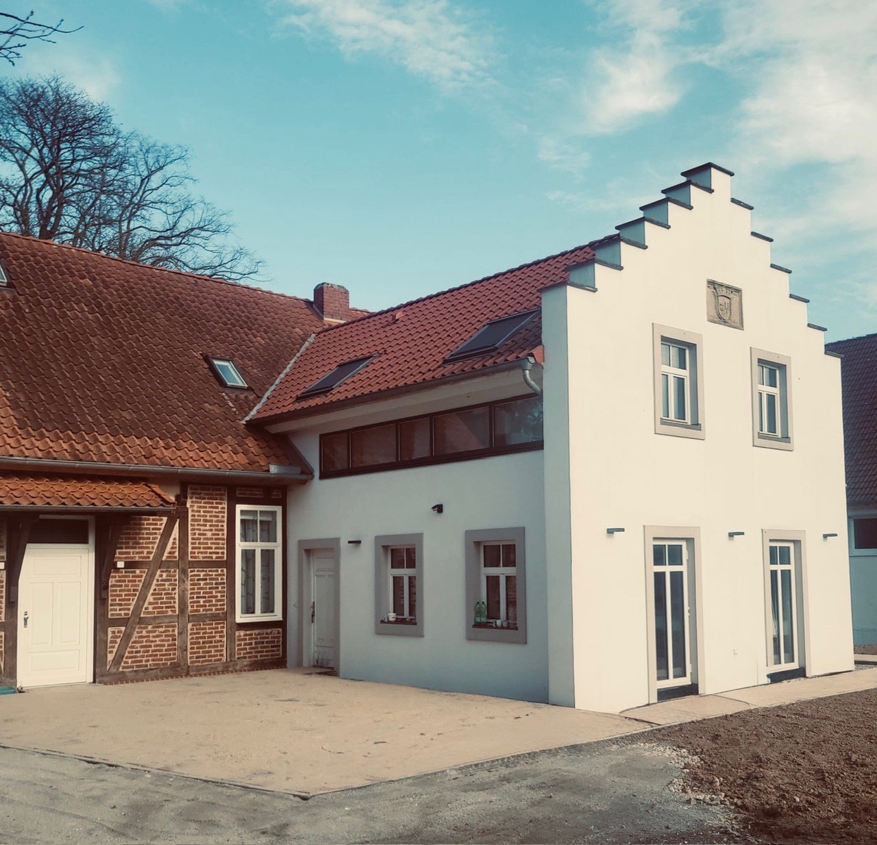 Saniertes Wohn- und Wirtschaftsgebäude mit weißem Treppengiebel und angrenzendem Fachwerkflügel