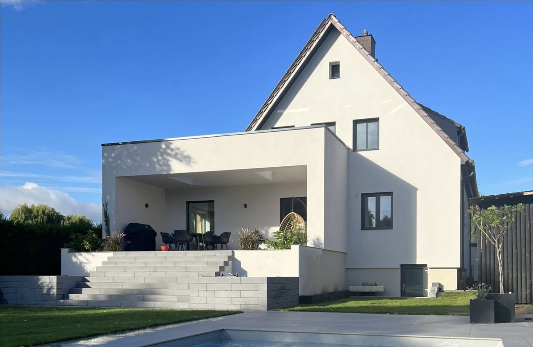 Das Haus nach dem Umbau: heller Anbau mit Flachdach und überdachter Terrasse